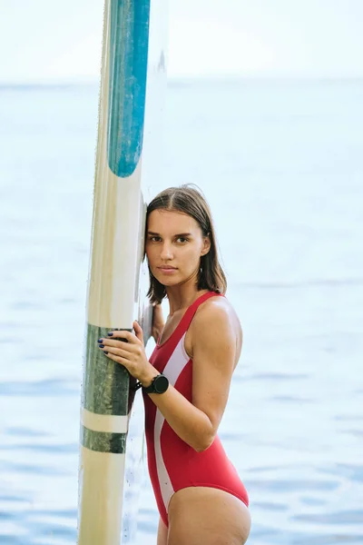 스포츠 리조트에서 휴가를 즐기는 동안붉은 수영복을 여성이 보드를 물가에서 — 스톡 사진