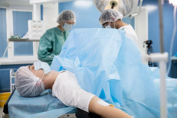 Jonge Mannelijke Patiënt Beschermend Masker Hoofddeksel Liggend Operatietafel Terwijl Twee — Stockfoto