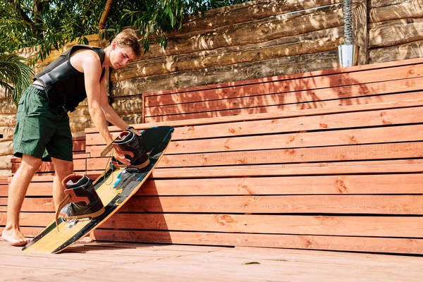 Giovane Surfista Pantaloncini Giubbotto Sicurezza Piegandosi Sulla Panchina Legno Nella — Foto Stock