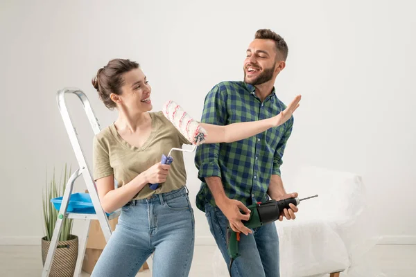 Jovem Brincalhão Cantando Rolo Pintura Enquanto Seu Marido Usando Broca — Fotografia de Stock