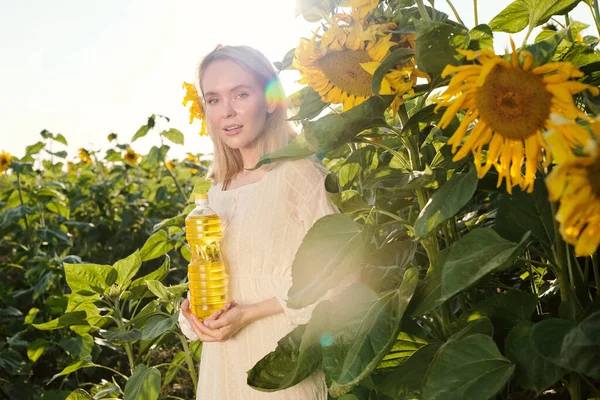 Ładna Blondynka Młoda Kobieta Białej Sukience Trzyma Butelkę Oleju Słonecznikowego — Zdjęcie stockowe