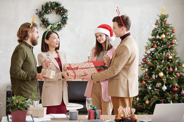 年轻优雅的商人给一位女同事送去了很多圣诞礼物 同时还向她在办公室的聚会表示祝贺 — 图库照片
