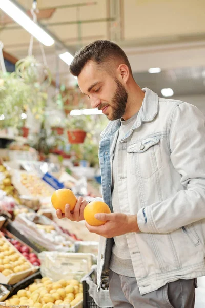 市場での免疫力を強化するために食品カウンターに立って柑橘類を購入髭の男の肩のビュー — ストック写真
