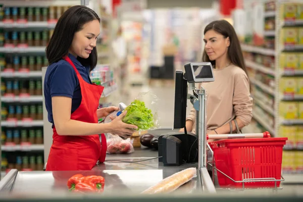 现代超级市场的店员卖新鲜蔬菜给难以辨认的女人 — 图库照片