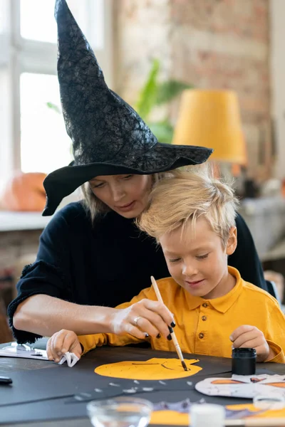 Серьёзная Молодая Мать Шляпе Ведьмы Сидит Сыном Коленях Помогает Ему — стоковое фото