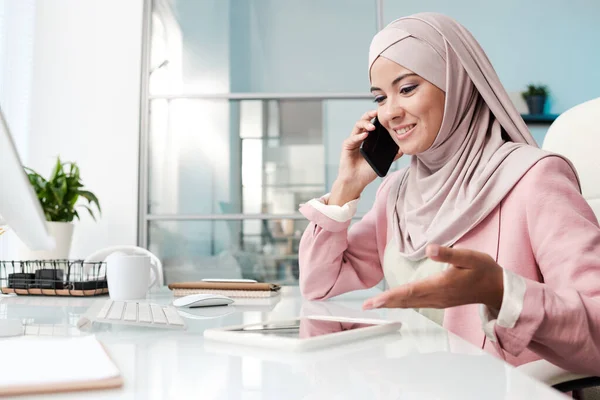 Mladá Veselá Muslimská Podnikatelka Hidžábu Mluví Klientem Mobilním Telefonu Ukazuje — Stock fotografie