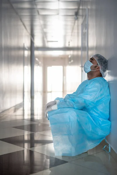 Trött Professionell Manlig Kirurg Skyddsarbetskläder Lutande Mot Väggen Korridoren Vid — Stockfoto