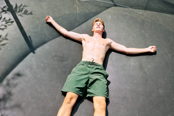 Young Cheerful Shirtless Man Green Shorts Lying Large Black Trampoline — Stock Photo, Image