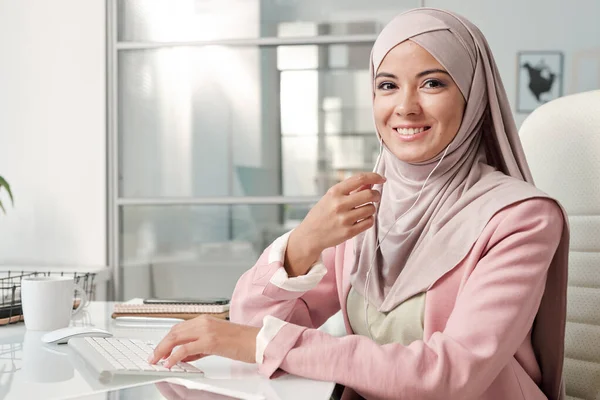 Vrolijke Moslim Zakenvrouw Oortelefoons Hijab Slimme Casualwear Zitten Aan Tafel — Stockfoto
