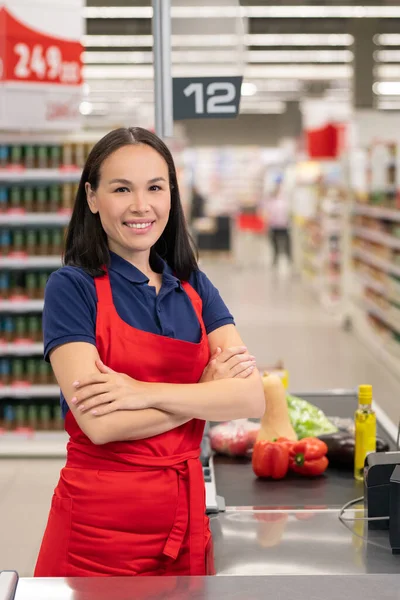 在超市工作的快乐女人坐在收银台前 微笑着看着相机 — 图库照片