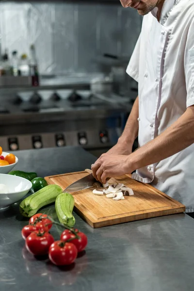 Mladý Kuchař Moderní Restaurace Bílé Uniformě Stojící Velkého Stolu Kuchyni — Stock fotografie