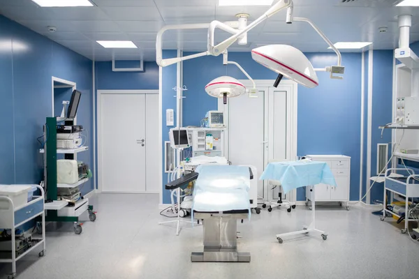 ランプ 診断装置及び一連の引き出しに囲まれた手術台を含む現代の診療所の手術室 — ストック写真