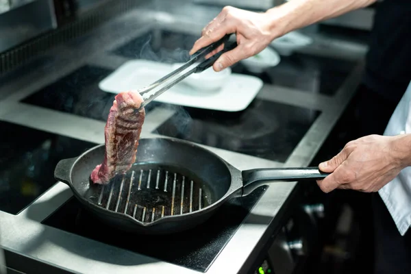 Mãos Jovem Chef Segurando Meio Torrado Pedaço Carne Sobre Frigideira — Fotografia de Stock