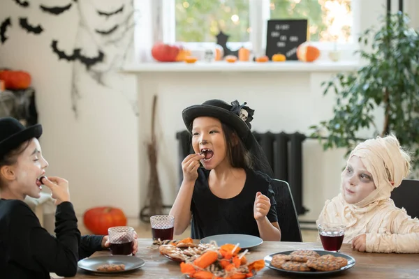 Skupina Šťastných Dětí Halloweenských Kostýmech Sedí Stolu Zdobeném Obývacím Pokoji — Stock fotografie