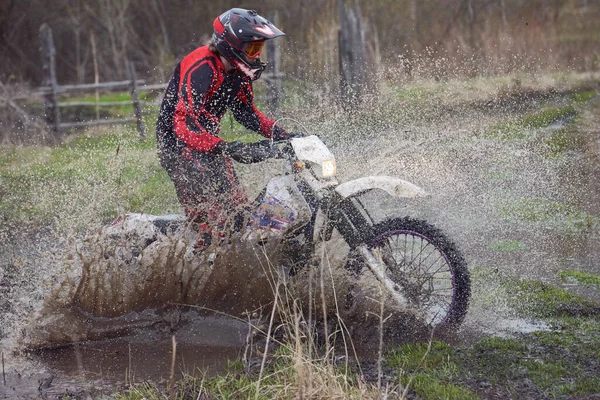 田舎でオートバイのライダーレースと大きな水たまりから水をはね — ストック写真