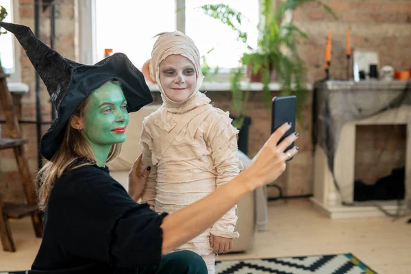 Attractive Young Mother Witches Hat Using Smartphone Selfie Camera While — Stock Photo, Image