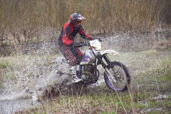 水たまりに対する未舗装の道路を田舎でオートバイのライダーレース — ストック写真