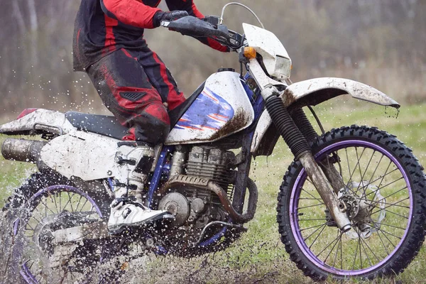 Motorcyclist racing in dirt while moving in front of camera