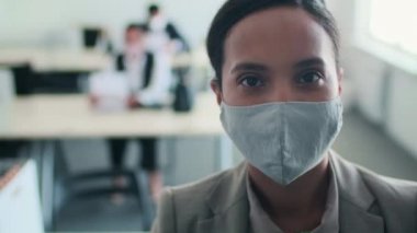 İşteki yalnızlık döneminde yüzüne koruyucu maske takan tanınmayan kadın ofis çalışanının kafa ve omuzları.