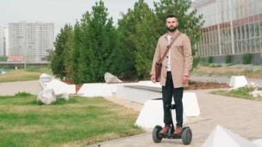 Açık güneşli bir günde parkta jiroskop süren modern melez yetişkin bir adamın eğik çekim görüntüleri.