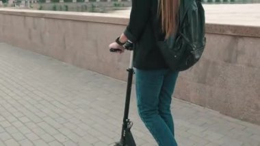 Şehir merkezindeki köprüde elektrikli scooter kullanan ve müzik dinleyip gezen genç melez kızın ayak parmaklarından baş aşağı görüntülerine kadar.