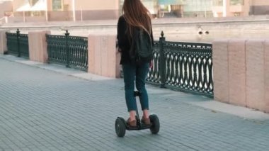 Arka planda, gün ışığında köprüde dengede duran bir kadının tam görüntüsü.