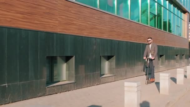 대낮에 현대식 사무실 건물을 달리는 스쿠터를 스마트 선글라스를 사람들의 — 비디오