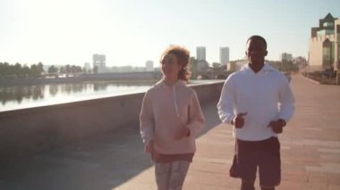 Arka planda nehir ve şehir köprüsü ile yapılan kardiyo çalışması sırasında atlama halatını atlayan atletizm sporcusu sahneleri.