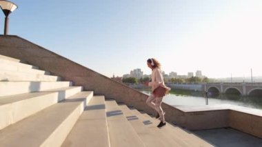 Güneşli bir günde şehir köprüsü ve nehir kenarında açık hava kardiyo antrenmanında merdivenlerden koşarak çıkan beyaz kadın fotoğrafları.