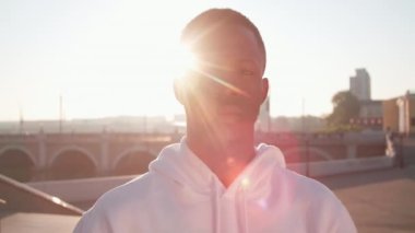 Spor giyim giymiş yakışıklı siyahi bir adamın kameraya yakından baktığı gün ışığında şehir merkezinde duran bir kamera.