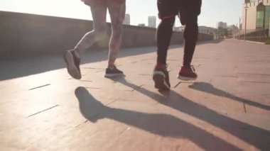 Gün ışığında kaldırımda koşu yapan kadın ve erkek ayaklarının tanınmaz haldeki düşük kesiminin görüntüleri.