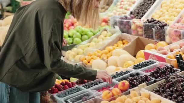 Handheld Medium Shot Van Vrolijke Blonde Vrouw Staan Bij Fruitkraam — Stockvideo