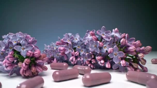 Макросъемка Проливания Фиолетовых Лекарственных Капсул Стол Красивыми Свежими Цветами Сирени — стоковое видео