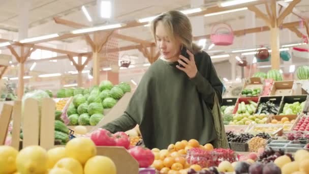 Medium Shot Van Gelukkige Jonge Vrouw Winkelen Voor Verse Komkommers — Stockvideo