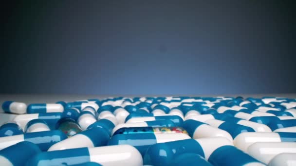 Panning Makro Shot Kolorowych Kapsułek Leków Białej Powierzchni Niebieskim Tle — Wideo stockowe