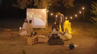 Genç bir grup arkadaş açık havada film gecesi yapıyorlar. Yiyecek, içecek ve projektörle. Yazın iyi vakit geçiriyorlar.