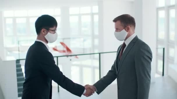 握手でお互いに挨拶保護マスクを身に着けている2人の認識できない男性オフィス労働者 サイドビューショット映像 — ストック動画