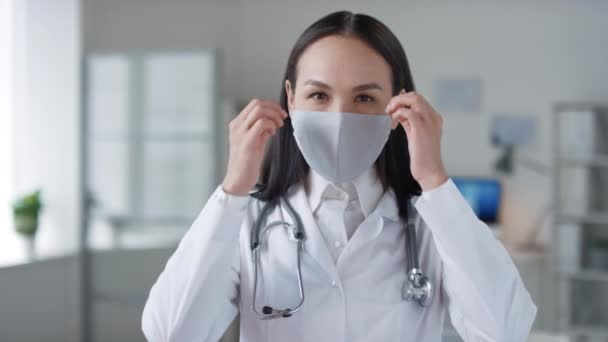 Hastanede Çalışan Neşeli Asyalı Kadının Koruyucu Maskesini Çıkartıp Kameraya Bakarken — Stok video