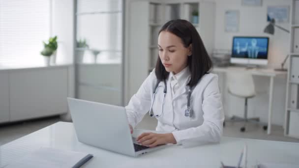Beyaz Önlüklü Asyalı Kadın Doktorun Orta Boy Portresi Ofisinde Oturmuş — Stok video