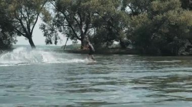 Genç sporcunun Wakeboard 'a yandan bindiği, gölde dengede durduğu, yaz günü su sıçrattığı hızlı görüntüler.