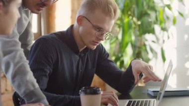 Yeni bir proje üzerinde çalışan genç çalışma ekibinin, gün ışığında büyük bir çalışma odasında oturup ayrıntıları ve stratejileri tartışması.