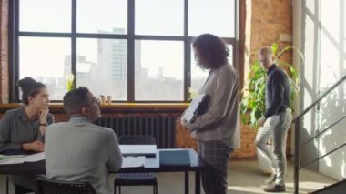 Genç iş adamının merdivenlerden inerken, iş arkadaşlarıyla yaklaşan projeyi tartışırken, fikir alışverişinde bulunurken ve beyin fırtınası yaparken orta boy fotoğrafı.