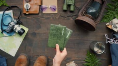 Doğrudan üzerinde seyahat ekipmanları olan tahta masaya pasaport koyan tanınmayan bir kadın yatıyordu.