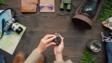 Tanınmayan bir kadının pusulayı açtığı ve üzerinde seyahat ekipmanları olan ahşap masaya yerleştirdiği en iyi manzara.