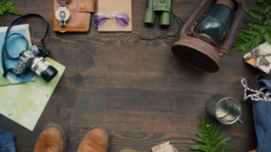 Tanınmayan bir kadının, üzerinde seyahat aksesuarları olan tahta masaya iki pasaport koyarkenki düz görüntüsü.