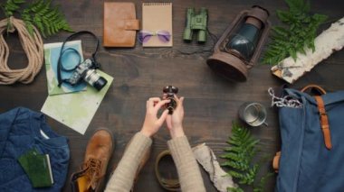 Kameranın önünde pusulayı açıp üzerinde seyahat aksesuarları olan ahşap masaya koyan tanınmamış bir kadının en iyi görüntüsü.
