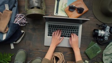 Tanınmayan bir kadının, dizüstü bilgisayarda yazı yazıp, ahşap masaya oturduğu, sonra da kapatıp götürdüğü en iyi görüntü. Masada yatan çeşitli seyahat aksesuarları