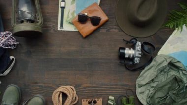 Tahta yüzeye yerleştirilmiş çeşitli seyahat aksesuarlarının düz görüntüsü. Masaya pasaport koyan tanınmayan bir kadın.