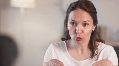 İyi görünümlü melez bir kadının yüzüne hafif dairesel hareketlerle nasıl ovuşturulacağını ya da maske takacağını söylediği orta boy yakın çekim.