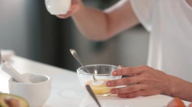 Sürahiden tabağa çırpılmış yumurtayla krema ekleyerek besleyici yüz maskesi yapmaya yakın plan.